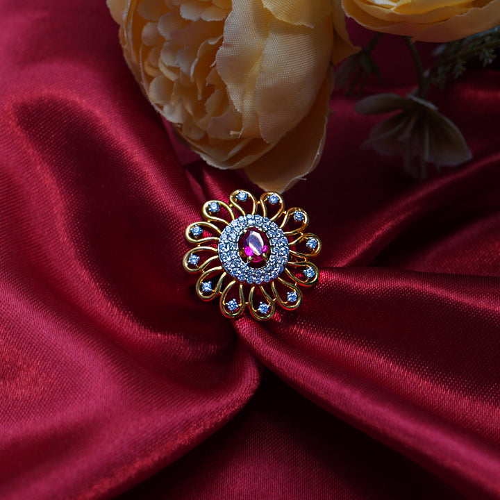 "A brilliant round gold ring with a striking red gemstone in the center, encircled by radiant diamonds.