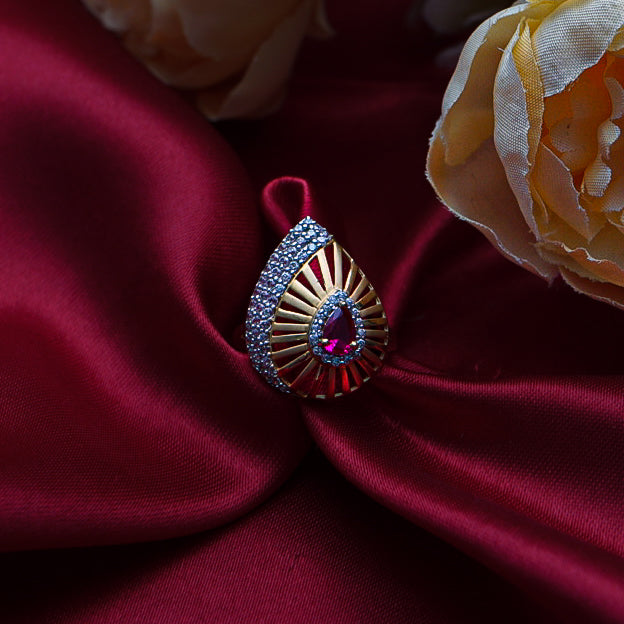 exquisite gold ring features a fiery red gemstone at its core, surrounded by sparkling diamonds.