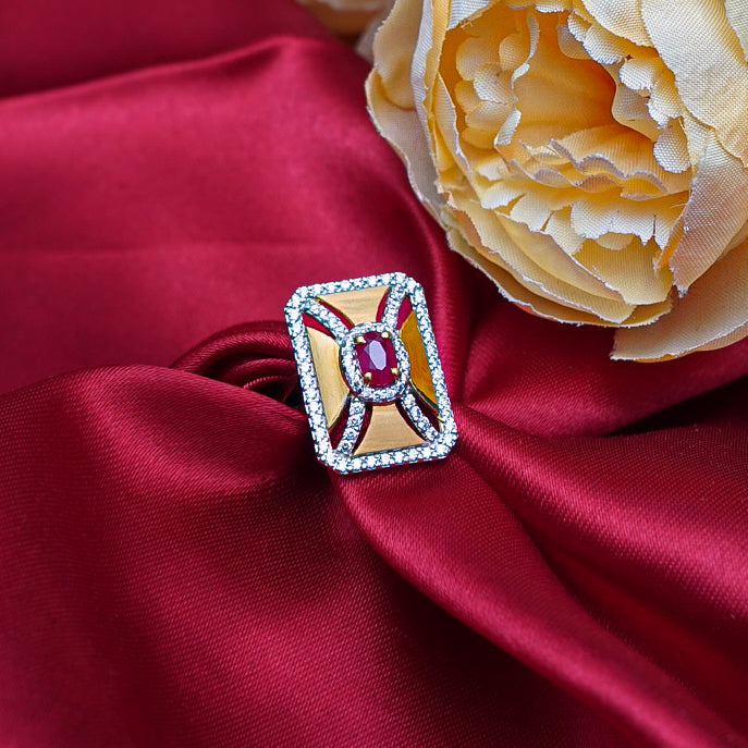 "This square gold ring with a fiery red gemstone and diamonds combines geometric elegance.