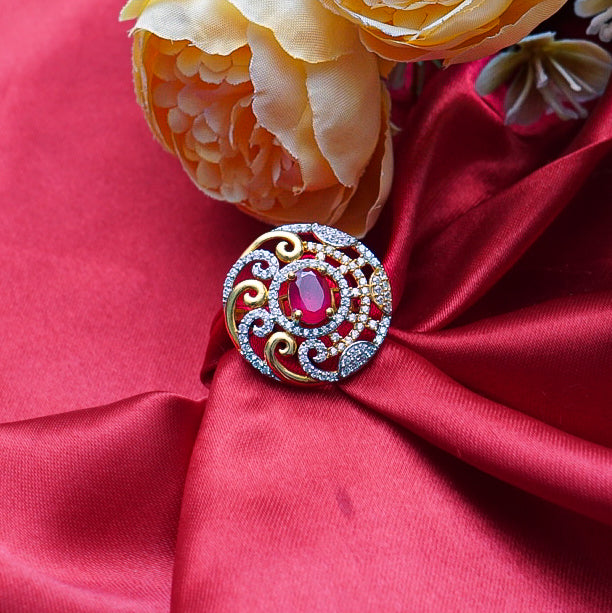 "A classic round gold ring with a captivating red gemstone at its center, surrounded by shimmering diamonds.