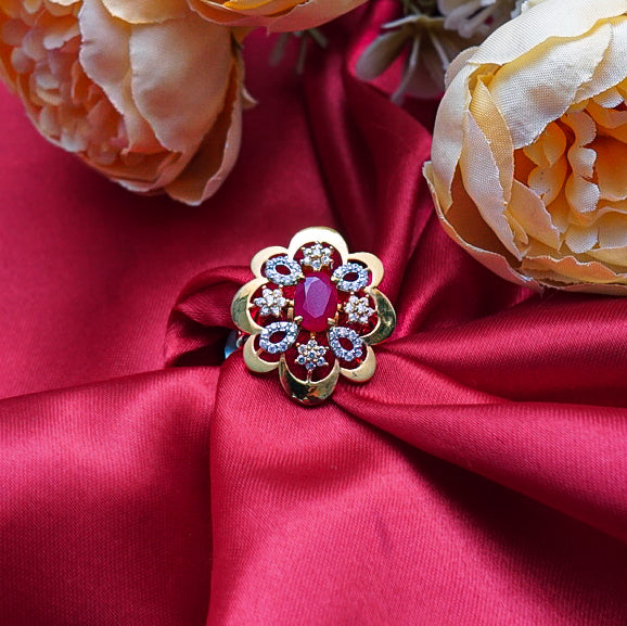 "A striking gold ring with a vibrant red gemstone at its core, complemented by diamonds.
