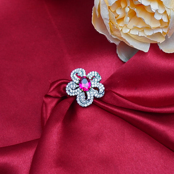 "A stunning flower-shaped gold ring featuring a vibrant red gemstone at its center with sparkling diamonds.